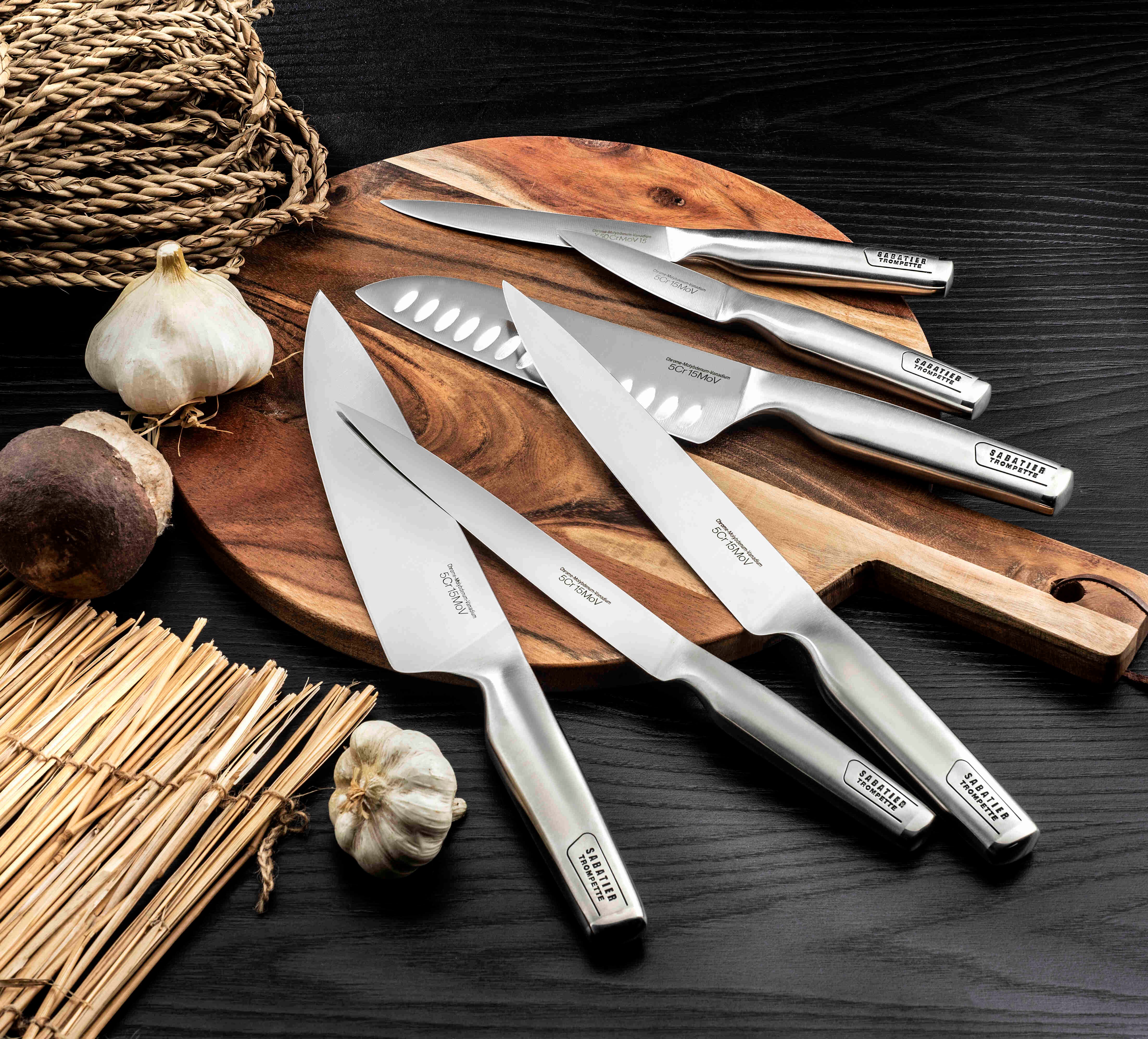 Photographie d'un set de couteaux de cuisine disposés sur une planche en bois.