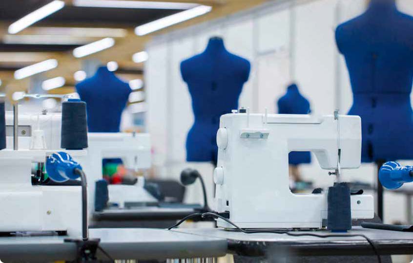 Vue des ateliers de production de la marque Lafont : des rangées de machines à coudre et de mannequins.