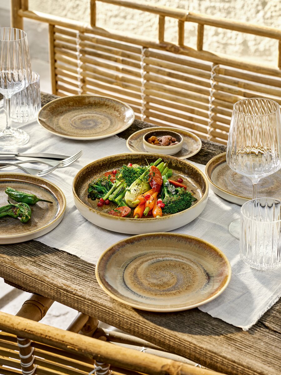 Vaisselle en porcelaine et verres à cocktail sur une table en bois.