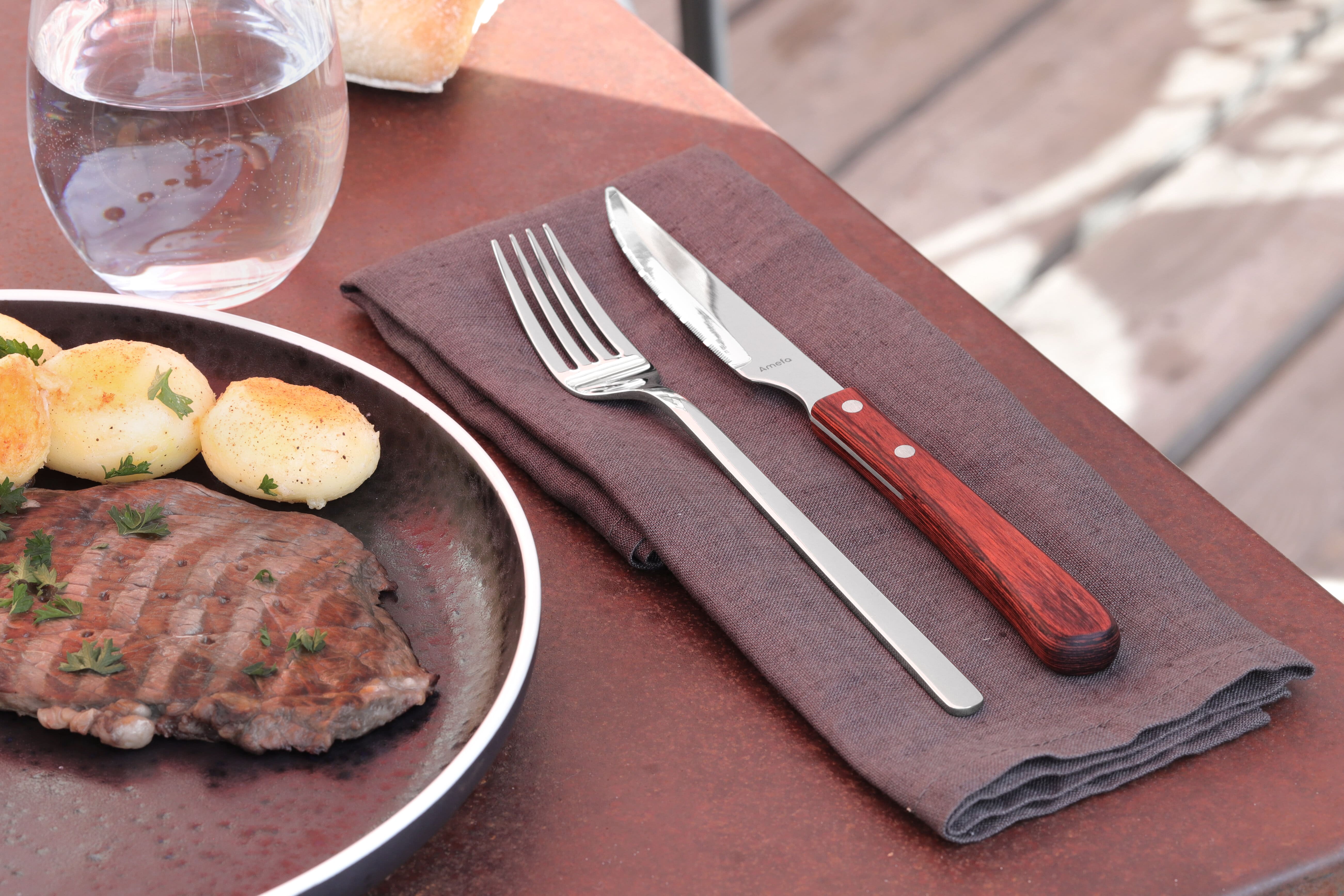 Deux couverts (un couteau et une fouchette) à steak et une assiette en porcelaine de la marque Amefa.