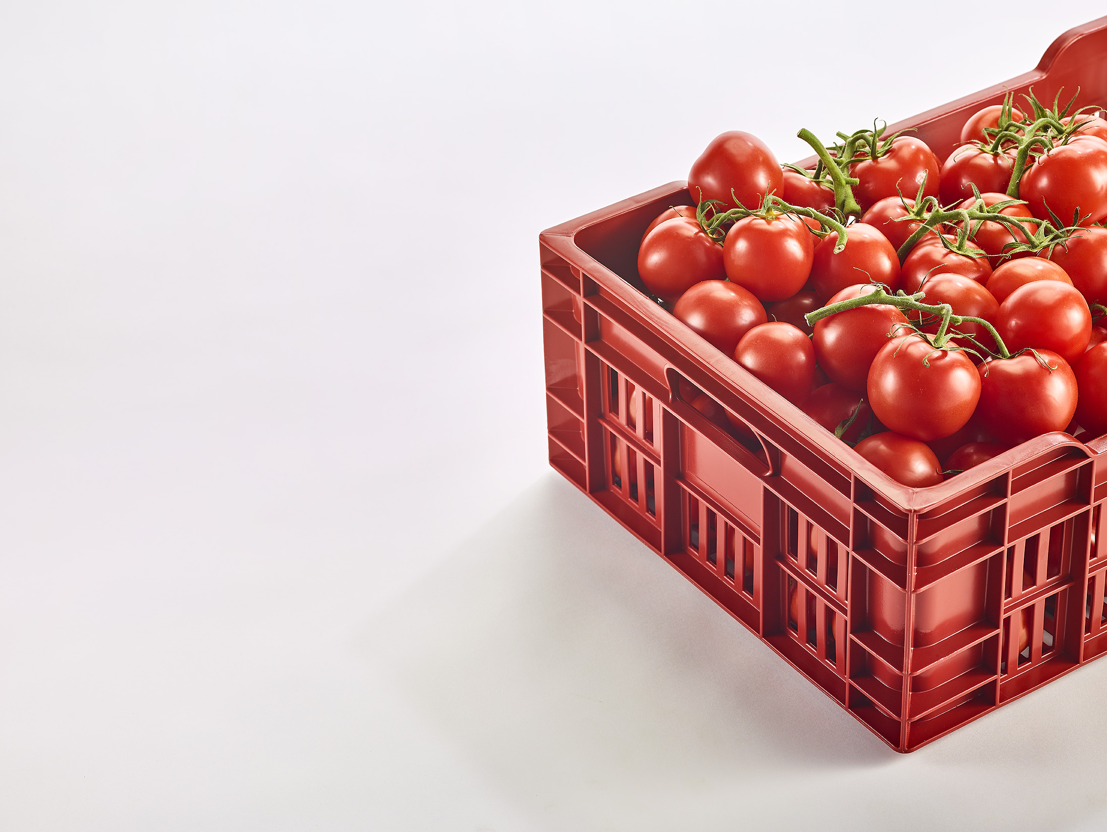 Caisse en copolyester rouge de la marque Gilac contenant des tomates.