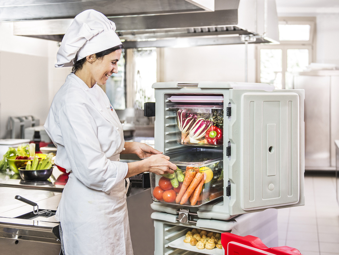 Employé de cuisine qui se sert dans un conteneur isotherme 