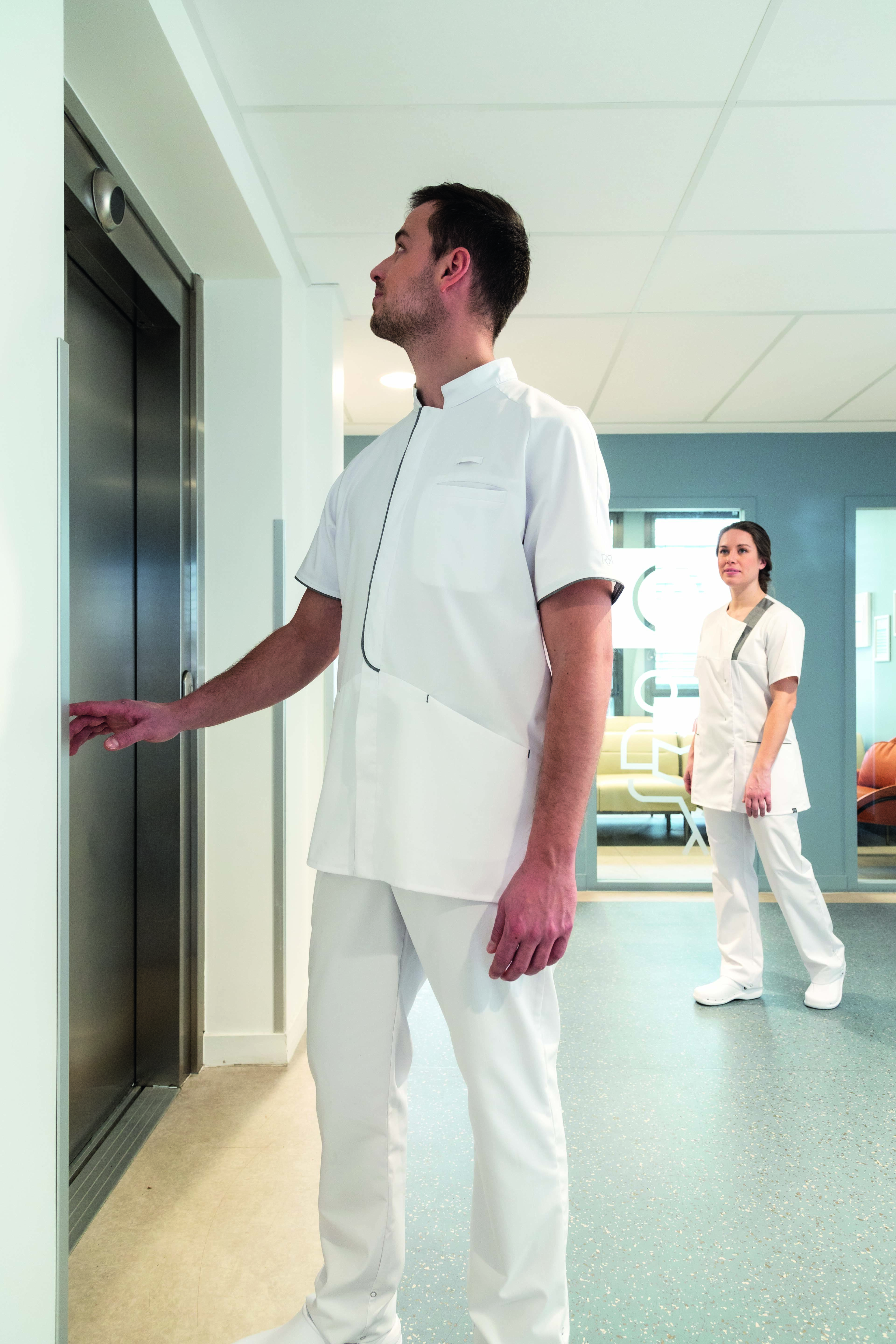 Dans un établissement de santé, deux soignants, un homme et une femme, portent des vêtements professionnels blancs de la marque Robur.