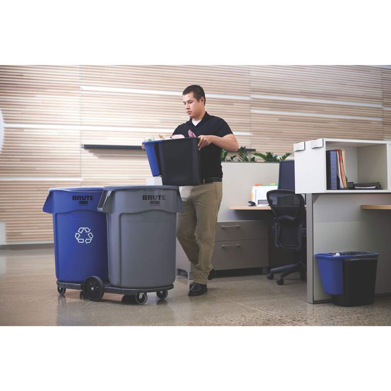 Un homme vide les petites poubelles de bureau dans deux poubelles de plus grande taille posées sur un chariot.